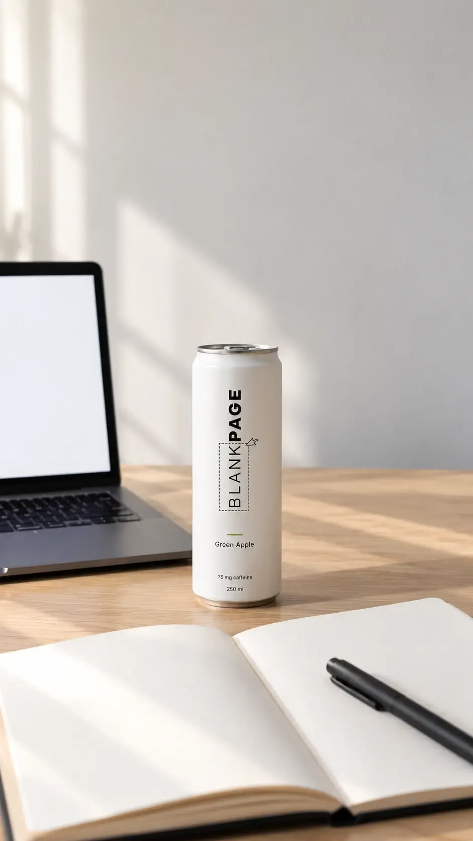A BLANKPAGE can on a wooden desk between an open laptop and a blank notebook with a pen